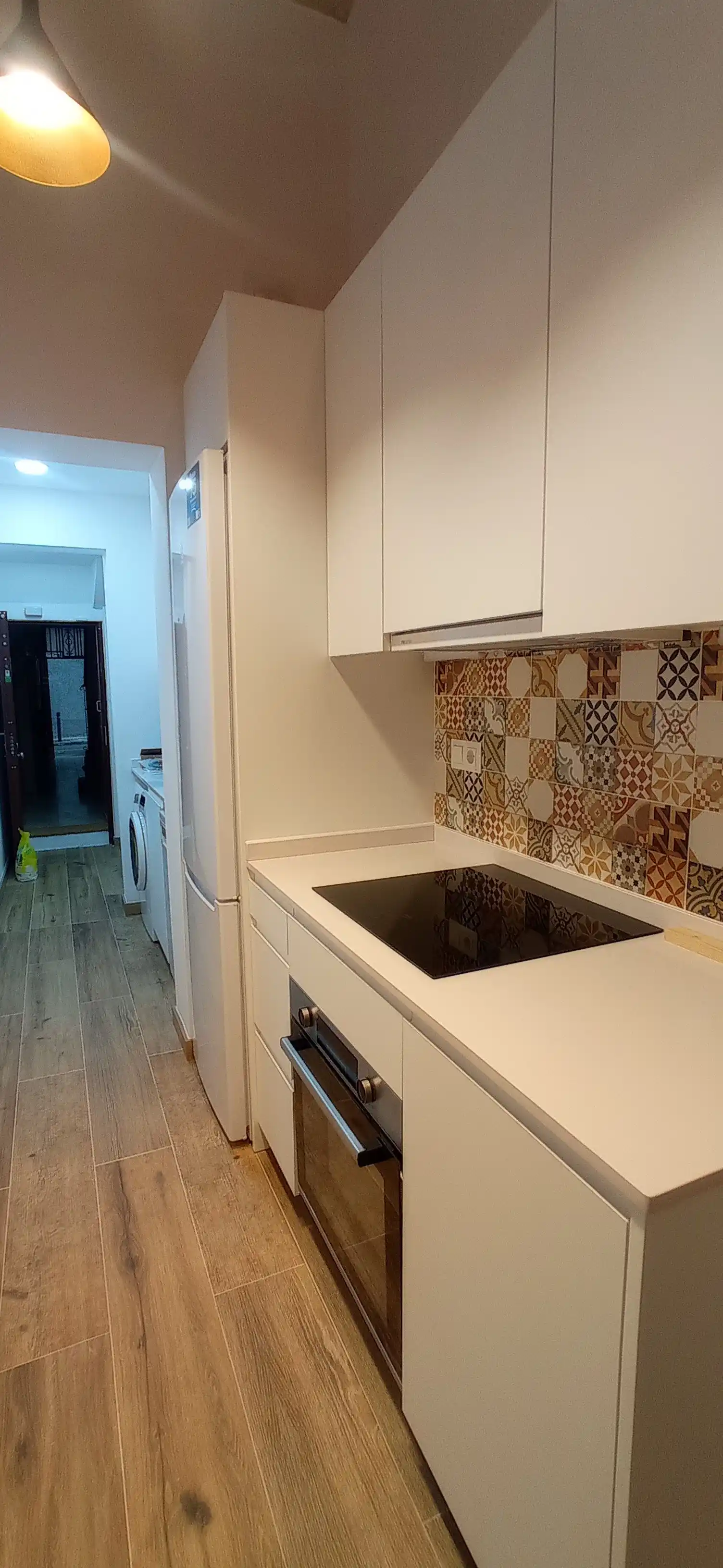 Reforma de cocina con mobiliario blanco, frontal de azulejo hidráulico y suelo laminado en Ripollet