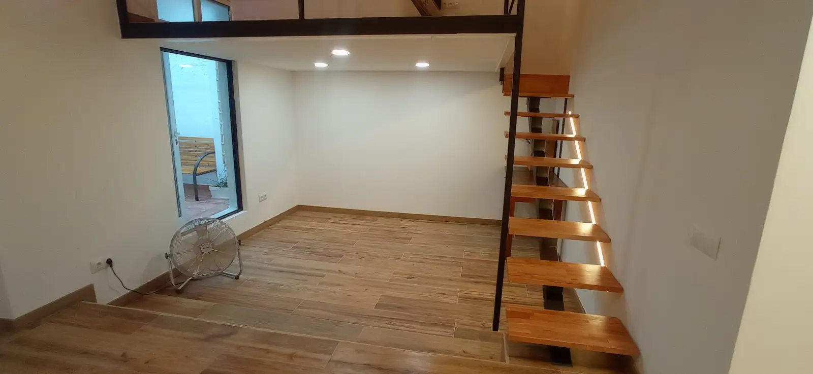 Reforma integral con escalera de madera volada e iluminación LED integrada en Ripollet